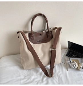 Detail of canvas tote bag with brown leather strap, laptop, and stylish lifestyle props