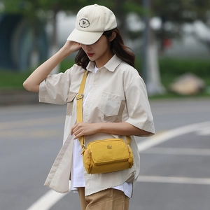 Scatto all'aperto di una borsa a tracolla in nylon giallo acceso con un cappello beige