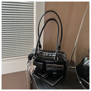 Nahaufnahme der schwarzen Retro-Kissentasche mit Krokodilmustertaschen und Herzanhänger