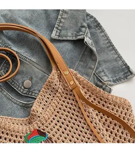 Detail of crochet tote bag with golden metal rivets and brown leather shoulder strap