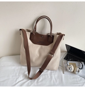 Detailed shot of large beige canvas tote bag with brown leather trim and shoulder strap