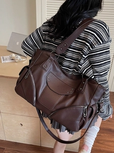 Sac à main marron avec rivets et étoiles, porté par un mannequin dans un bureau moderne