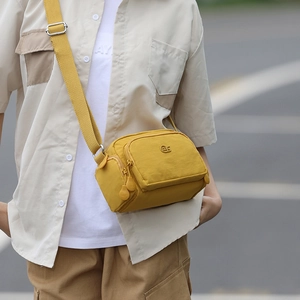 Foto all'aperto della borsa a tracolla in nylon giallo brillante con design multi-tasca