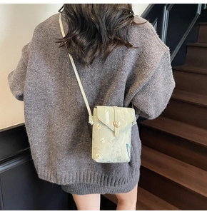 Détail du sac de téléphone vert clair avec broderie marguerite et fermoir coeur