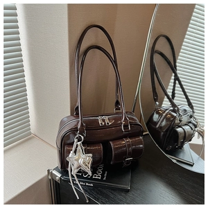 Detail einer dunkelbraunen Ledertasche mit geprägten Fronttaschen und Sternenanhänger
