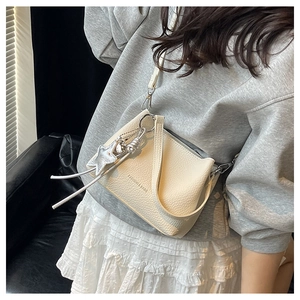 Detail of creamy white pebble leather bucket bag with silver star tassel charm