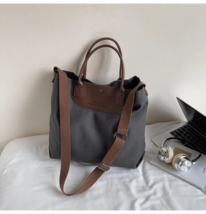 Detail of dark grey canvas tote with brown leather handle and embossed logo text