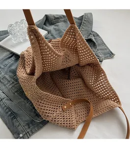 Close-up of hollow knit tote bag with brown leather shoulder straps and metal rivets