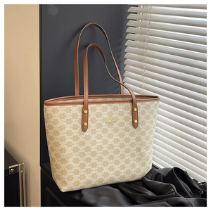 Close-up of texture tote bag with brown leather handles and golden metal rivets