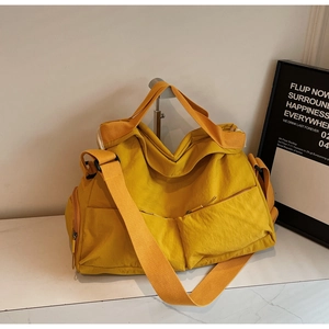 Macro shot of the vibrant yellow nylon tote featuring multi-pocket detail and water-resistant fabric