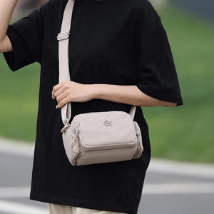 Dettaglio borsa a tracolla in nylon grigio con tasche a zip e tracolla regolabile