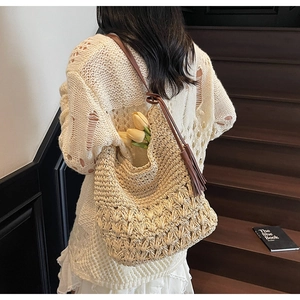 Detail of hand-woven straw bag featuring decorative long tassels and fine crochet texture
