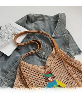 Detail of hand-woven crochet tote bag with girl embroidery and brown leather straps