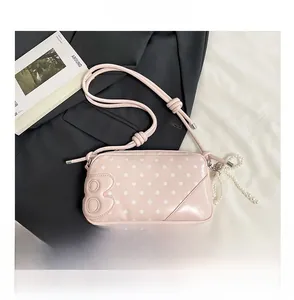 Pink polka dot crossbody bag detail with pearl strap and embossed side number
