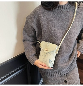 Détail d'un sac en toile brodé avec boucle de cœur dorée et fine bandoulière réglable