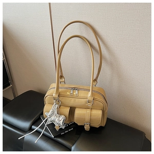 Detail der gelben Lacklederhandtasche mit zwei Fronttaschen und Stern-Metallanhänger