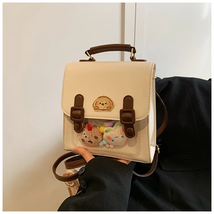 Detail of cute beige ita bag with transparent window and plush charms for school style
