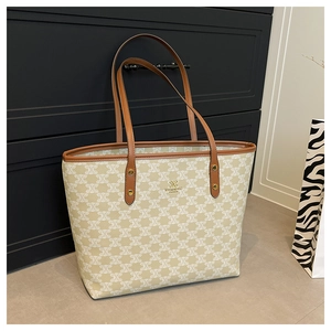 Detail of canvas tote bag with brown leather trim and golden metal rivet reinforcement