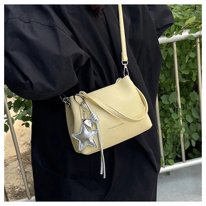Detail of yellow lychee leather bucket bag with silver star and heart charms for women
