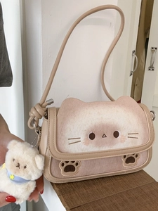 Borsa a tracolla beige a tema gatto con ricami carini e ciondolo a forma di orso sul tavolo