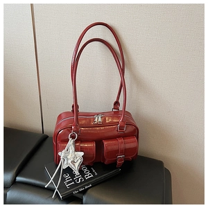 Detail der burgunderroten glänzenden Lederhandtasche mit Ziertaschen und Silberanhängern