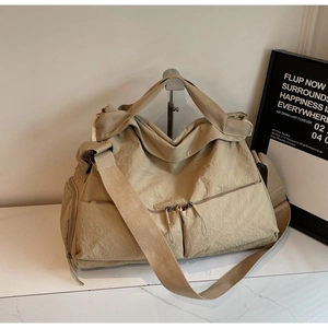 Detail of khaki nylon tote bag with functional zipper pockets on a marble surface