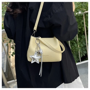 Detail of light yellow hobo bag with pebble texture and silver star charm