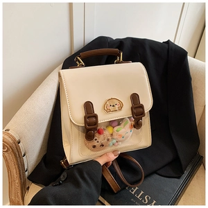 Close-up of a retro cream mini backpack with a clear PVC window and cute plush charms