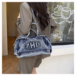 Dettaglio della borsa in denim vintage blu con ricamo ZHD portata da una modella