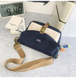 Detail of navy blue and beige canvas messenger bag with adjustable strap and outdoor charms