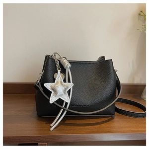 Detail of black lychee grain leather bucket bag with silver star charm and embossed text