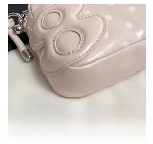 Detail of pink polka dot bag featuring precision stitching and silver ball zipper pull