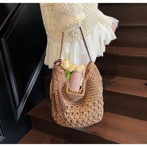 Detail of woven straw shoulder bag with hollow texture and matching brown tassels