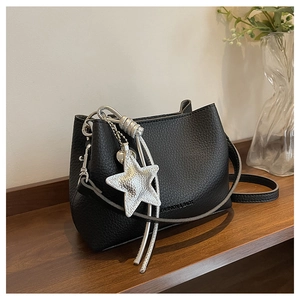 Détail du sac seau noir en cuir avec pendentif étoile argenté et pompon à franges