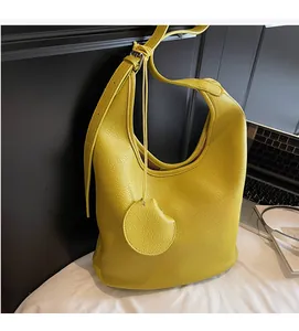 Detail of yellow lychee grain leather hobo bag with matching round charm accessory