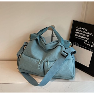 Detail of light blue casual crossbody bag with dual front zipper pockets and adjustable strap