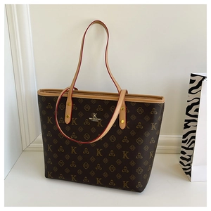 Detailed macro view of brown tote bag featuring branded monogram patterns and gold logo