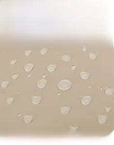 Gros plan sur le tissu beige imperméable avec gouttes d'eau montrant l'effet perlant