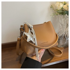 Detailed view of brown lychee grain leather bucket bag with a silver star pendant and tassel