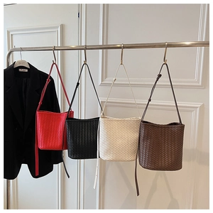 Detail of woven bucket bags in red black beige and brown with slim leather straps