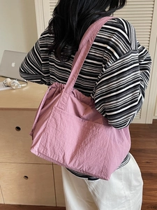 Pink oversized nylon tote bag with pleated texture shown on a female model's shoulder