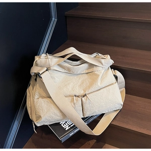 Close-up of beige nylon tote bag with crinkled texture and dual front zipper pockets