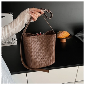 Close-up of brown woven leather bucket bag featuring a red drawstring inner pouch
