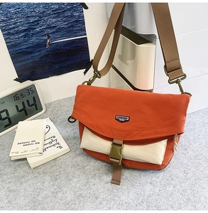 Detail of orange nylon crossbody bag with buckle closure and wide adjustable shoulder strap