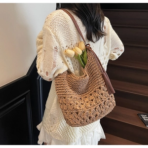 Close-up of woven straw tote bag featuring brown leather strap and stylish tassel detail