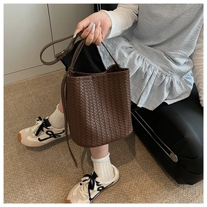 Detail of dark brown woven leather bucket bag with adjustable shoulder strap for women