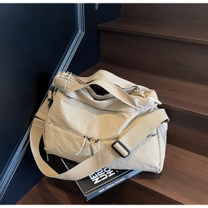 Close-up of beige nylon tote bag with wide strap on a dark wooden staircase