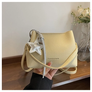 Close-up of cream yellow leather bucket bag with star pendant and silver hardware