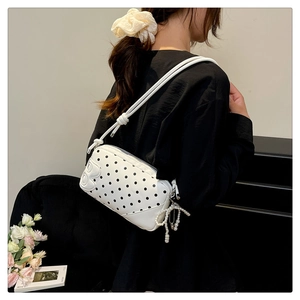 Detail of white polka dot shoulder bag with B logo and pearl bow charm accessory