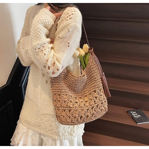 Detailed close-up of woven hollow-out pattern and leather tassel on straw tote bag